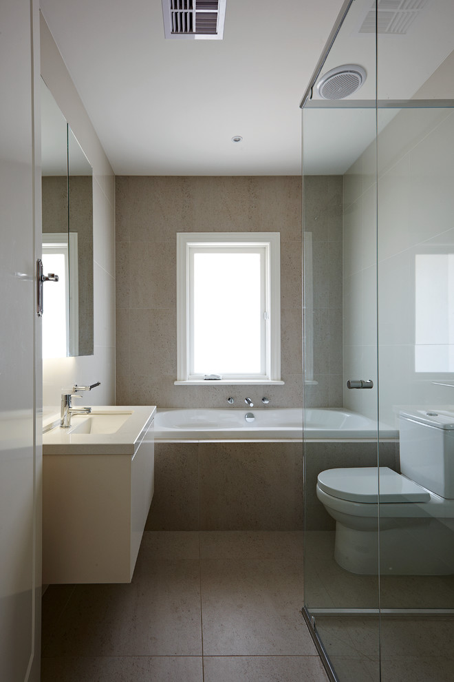 Inspiration for a medium sized shower room bathroom in Melbourne with a submerged sink, flat-panel cabinets, white cabinets, quartz worktops, a built-in bath, a built-in shower, a two-piece toilet, beige tiles, stone slabs, white walls and travertine flooring.