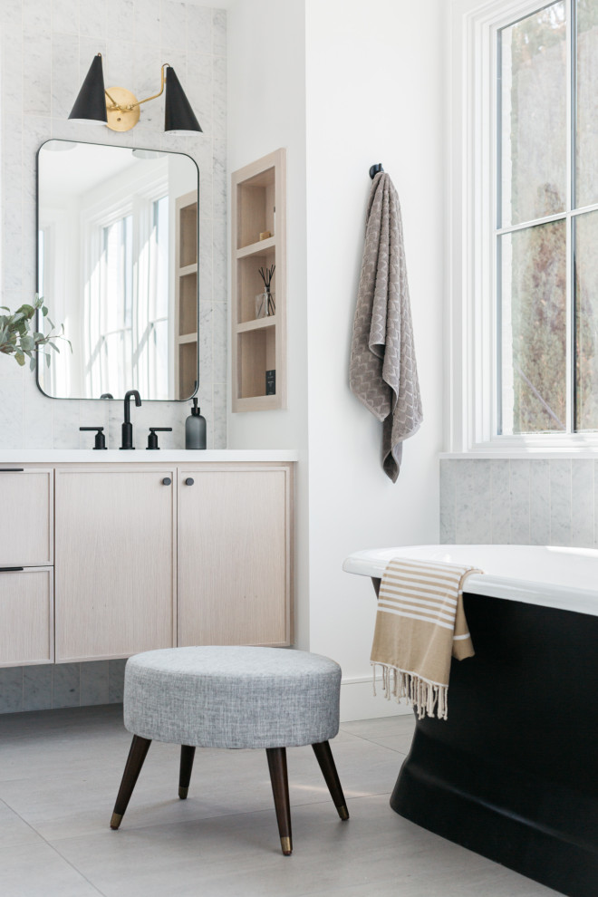 Photo of a country bathroom in Los Angeles with flat-panel cabinets, light wood cabinets, a freestanding bath, white tiles, white walls, a submerged sink, grey floors, white worktops and a floating vanity unit.