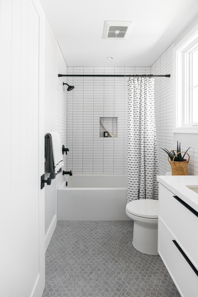 Lantlig inredning av ett vit vitt en-suite badrum, med ett undermonterad handfat, bänkskiva i kvarts, grått golv, släta luckor, vita skåp, ett badkar i en alkov, en dusch/badkar-kombination, vit kakel, vita väggar, mosaikgolv och dusch med duschdraperi