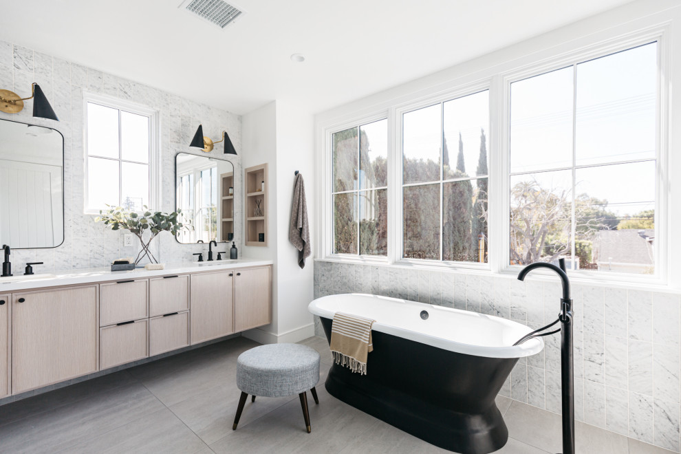 Large country bathroom in Los Angeles with porcelain flooring, grey floors, flat-panel cabinets, light wood cabinets, a freestanding bath, white tiles, white walls, a submerged sink, white worktops, double sinks and a floating vanity unit.