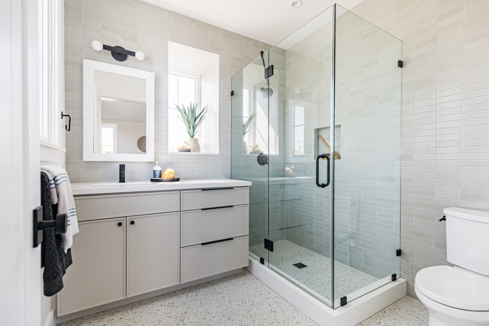 Inredning av ett lantligt vit vitt en-suite badrum, med marmorkakel, ett undermonterad handfat, bänkskiva i kvarts, grått golv, dusch med gångjärnsdörr, släta luckor, grå skåp, grå kakel och mosaikgolv