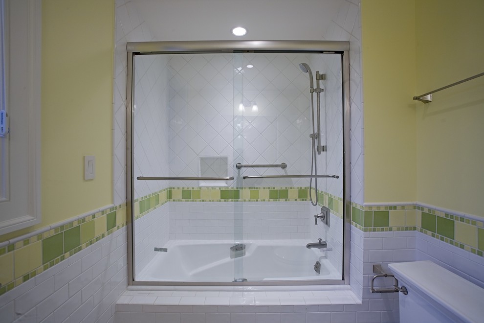 На фото: ванная комната с ванной в нише, душем над ванной, зеленой плиткой, желтыми стенами и душем с раздвижными дверями с