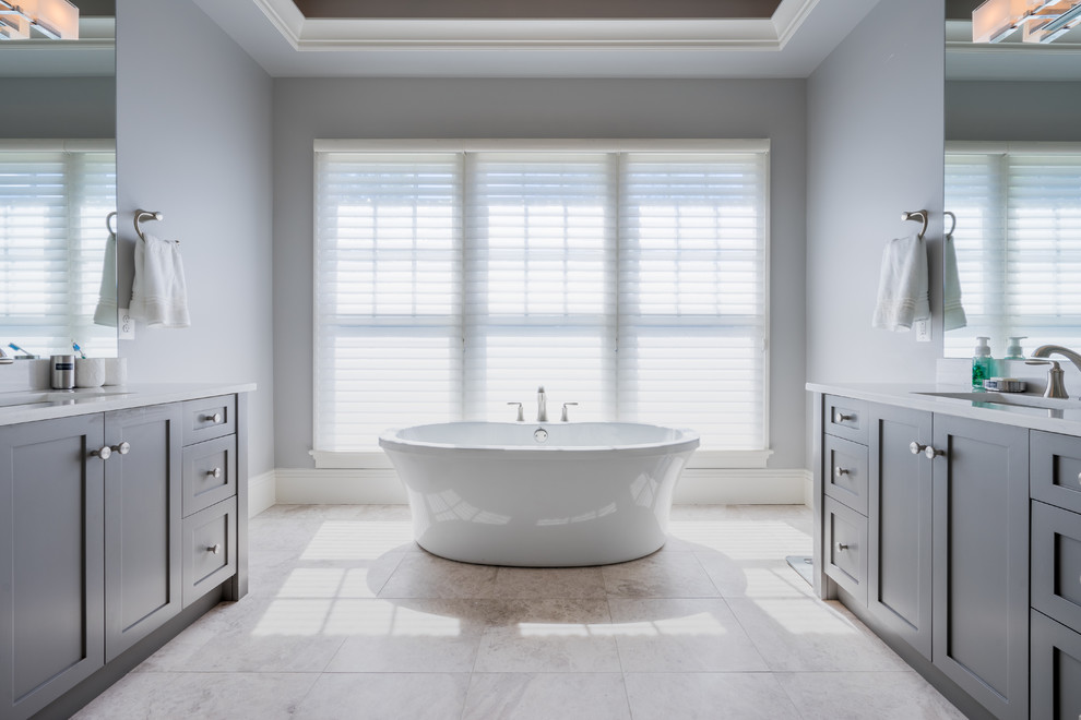 Idéer för ett mellanstort klassiskt en-suite badrum, med luckor med infälld panel, grå skåp, ett fristående badkar, en toalettstol med separat cisternkåpa, ett undermonterad handfat, marmorbänkskiva, en dusch i en alkov, grå väggar och kalkstensgolv