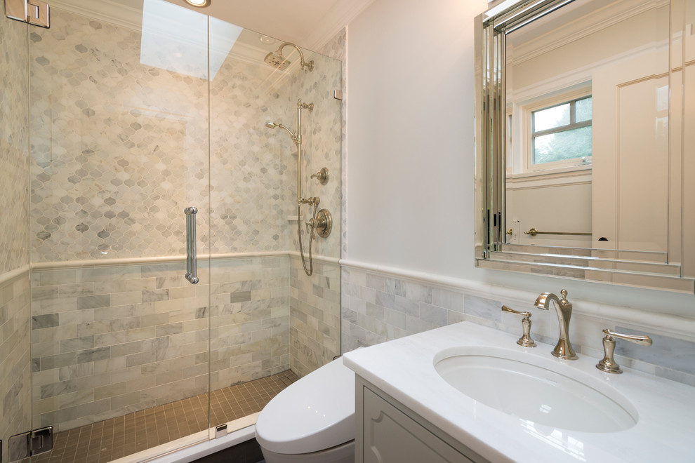 Photo of a large classic ensuite bathroom in Vancouver with shaker cabinets, white cabinets, a freestanding bath, a corner shower, a one-piece toilet, multi-coloured tiles, glass tiles, grey walls, porcelain flooring, a submerged sink and quartz worktops.