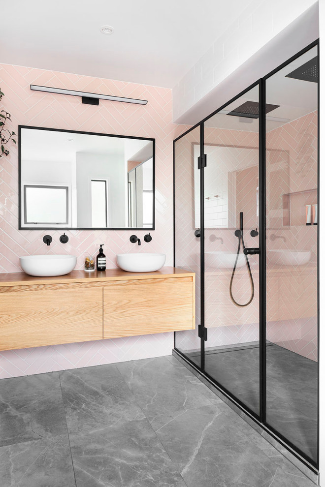 На фото: главная ванная комната в современном стиле с бежевыми фасадами, душем в нише, розовой плиткой, керамической плиткой, белыми стенами, полом из цементной плитки, раковиной с несколькими смесителями, столешницей из дерева, серым полом, душем с распашными дверями, бежевой столешницей, тумбой под две раковины и подвесной тумбой