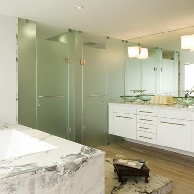 This is an example of a modern bathroom in San Francisco with marble worktops and light hardwood flooring.