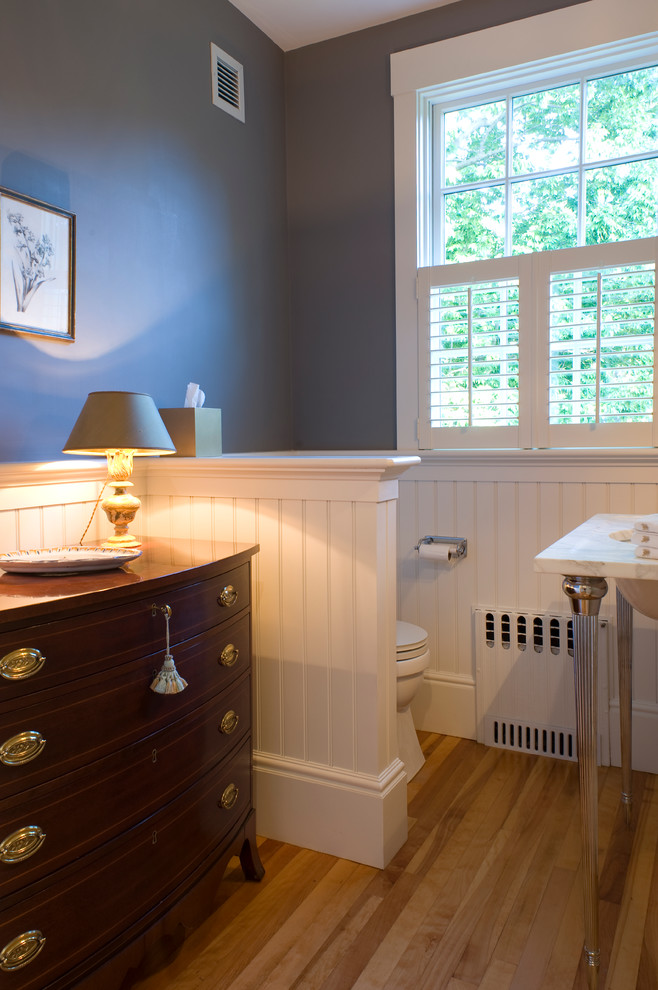 Immagine di una stanza da bagno chic di medie dimensioni con lavabo a colonna, consolle stile comò, ante in legno bruno, WC a due pezzi, pareti blu e parquet chiaro