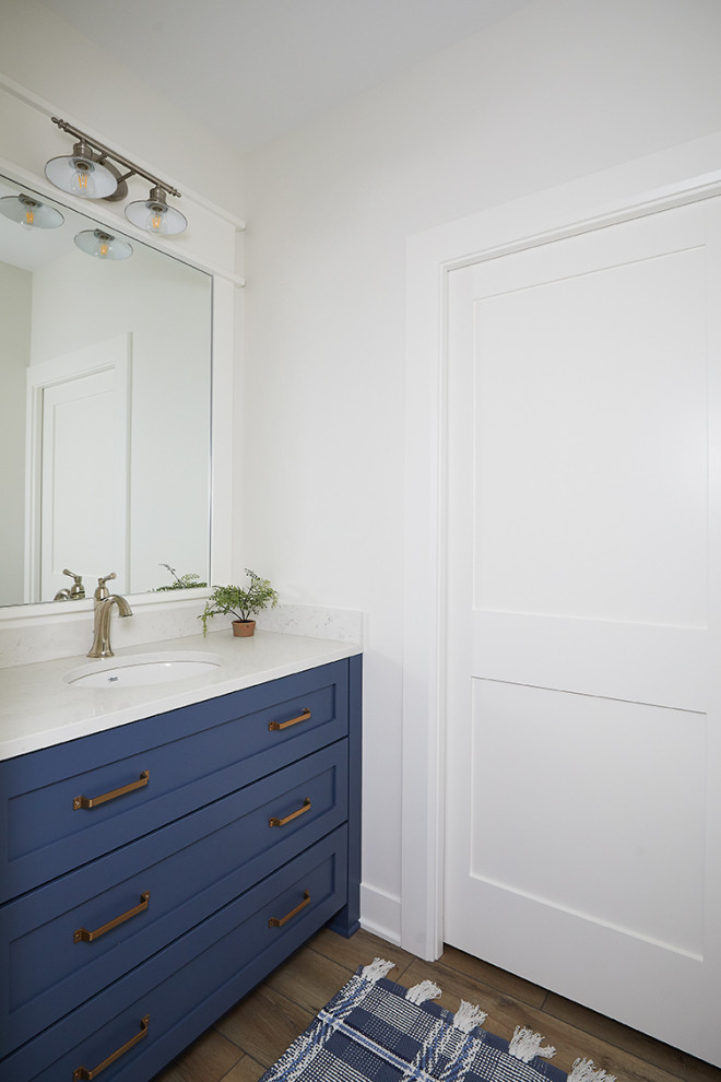 Cette image montre une salle d'eau avec un placard avec porte à panneau encastré, des portes de placard bleues, un mur blanc, parquet clair, un lavabo encastré, un plan de toilette en marbre, un sol marron, un plan de toilette blanc, meuble simple vasque et meuble-lavabo encastré.