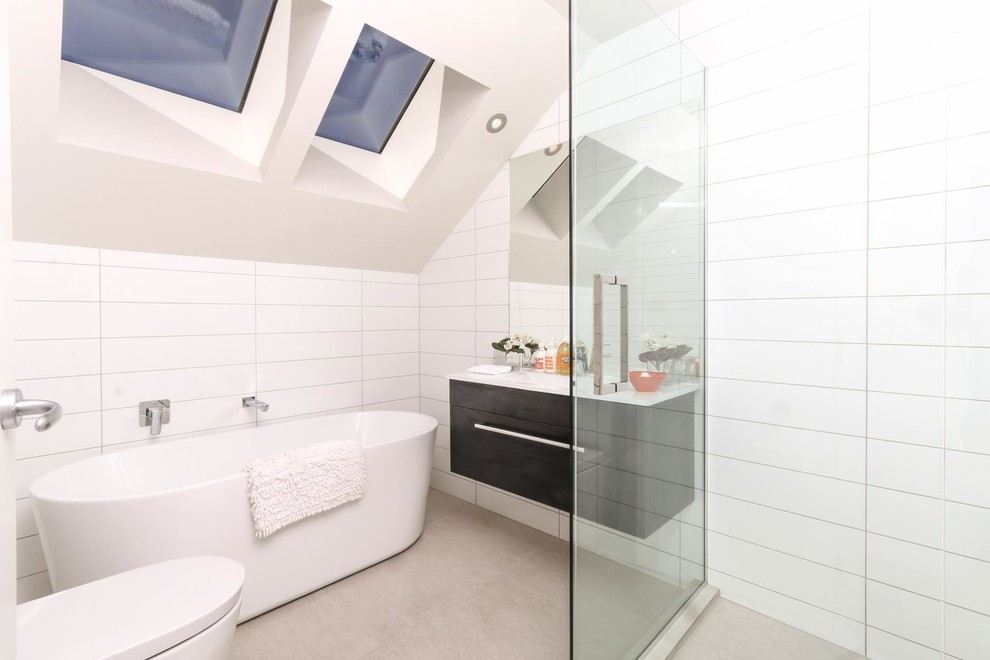 Small contemporary ensuite bathroom in Auckland with freestanding cabinets, dark wood cabinets, a freestanding bath, a walk-in shower, a one-piece toilet, white tiles, a console sink, laminate worktops, metro tiles, porcelain flooring, white walls and an open shower.