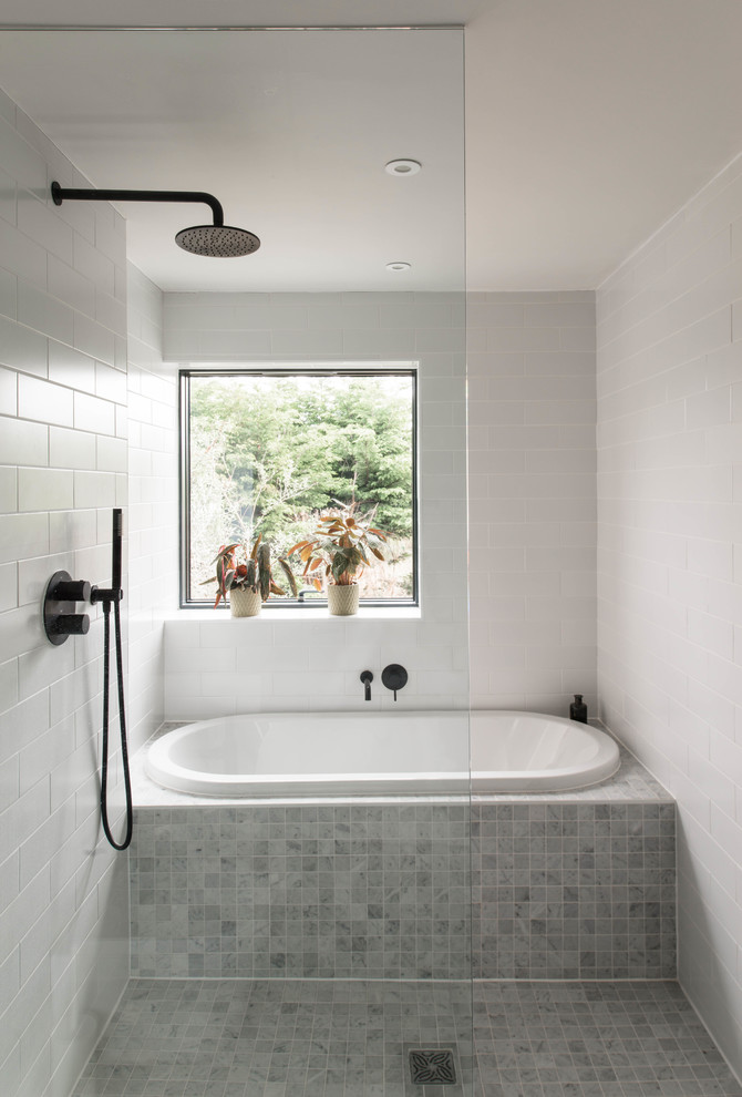 Inspiration for a modern wet room bathroom in London with glass-front cabinets, white cabinets, a built-in bath, a wall mounted toilet, grey tiles, grey walls, marble flooring, a wall-mounted sink, marble worktops, grey floors and an open shower.