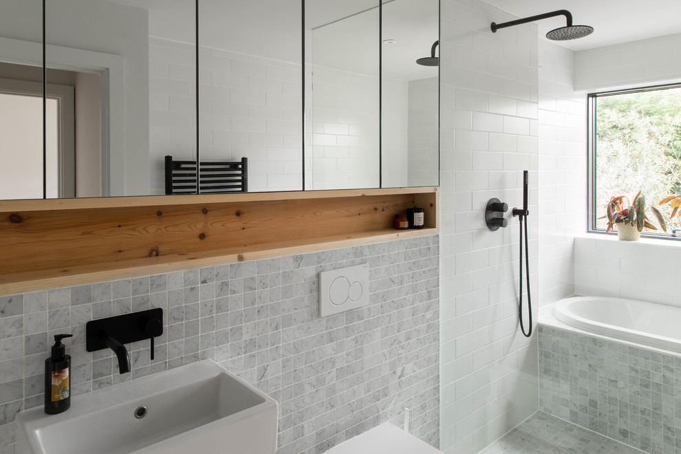Idéer för funkis badrum, med luckor med glaspanel, vita skåp, ett platsbyggt badkar, våtrum, en vägghängd toalettstol, grå kakel, grå väggar, ett väggmonterat handfat, marmorbänkskiva och med dusch som är öppen