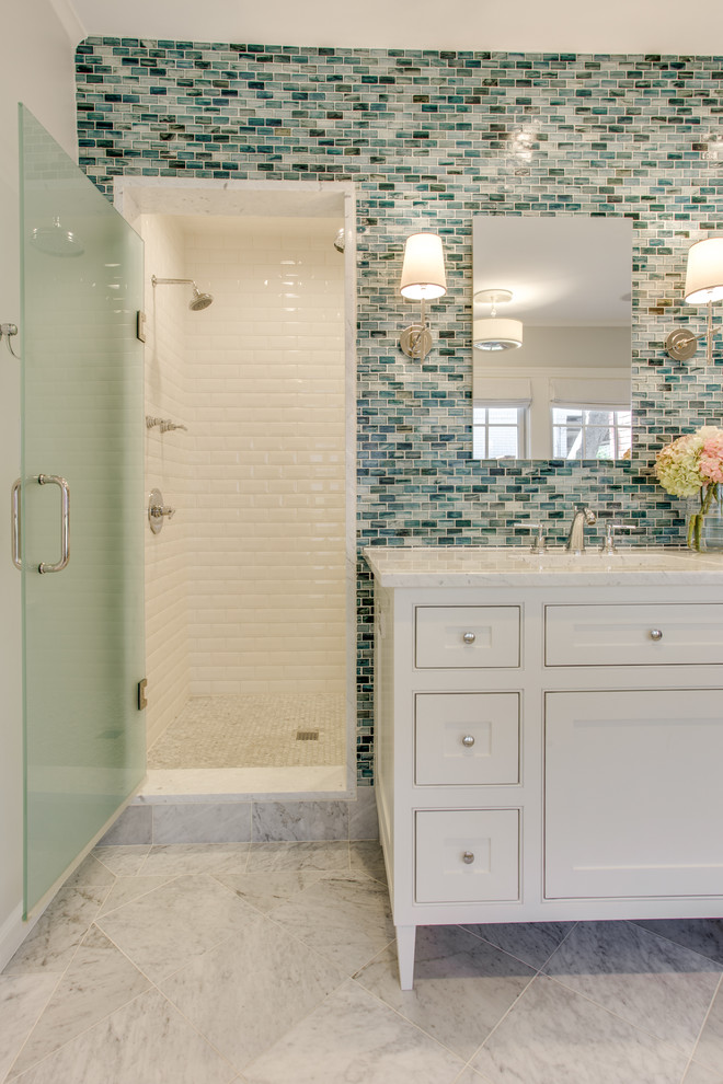 Cette photo montre une douche en alcôve chic pour enfant avec un placard à porte affleurante, des portes de placard blanches, une baignoire indépendante, un carrelage bleu, un mur gris, un sol en marbre, un lavabo encastré et un plan de toilette en marbre.