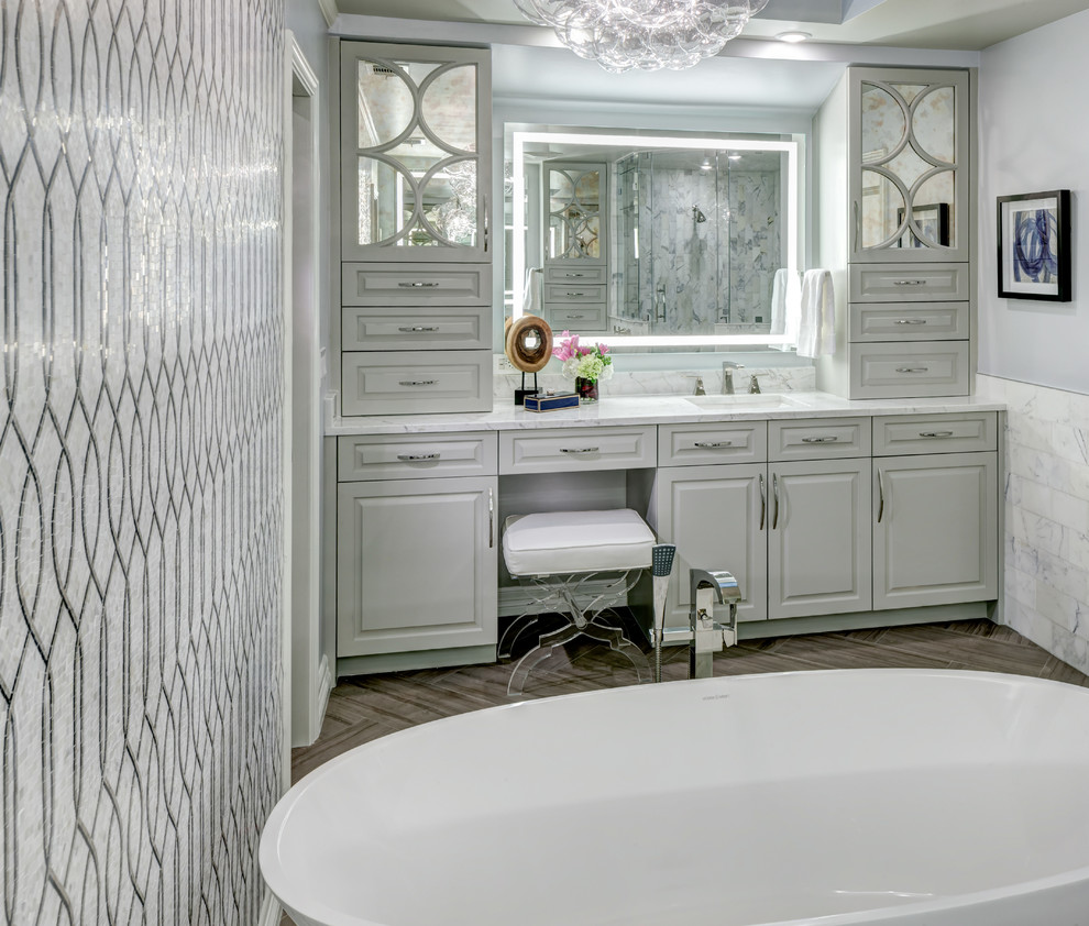 Inspiration for a large transitional master gray tile and white tile medium tone wood floor bathroom remodel in Dallas with raised-panel cabinets, white cabinets, a one-piece toilet, gray walls, an undermount sink and marble countertops