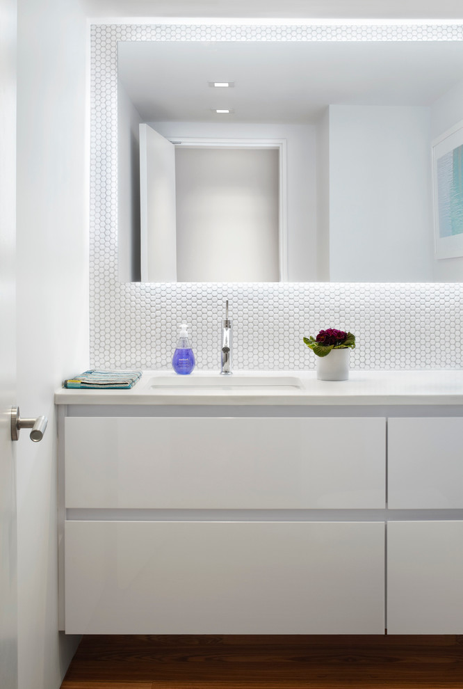 Modelo de cuarto de baño actual pequeño con armarios con paneles lisos, puertas de armario blancas, sanitario de una pieza, paredes blancas, aseo y ducha, lavabo bajoencimera y encimera de acrílico