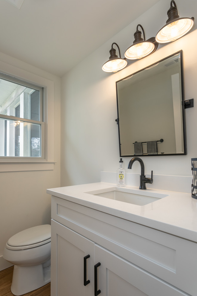Foto på ett litet funkis vit badrum med dusch, med skåp i shakerstil, vita skåp, en toalettstol med separat cisternkåpa, vita väggar, mellanmörkt trägolv, ett undermonterad handfat, bänkskiva i kvartsit och beiget golv
