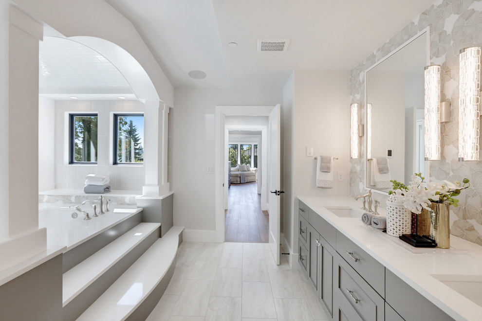 Medium sized contemporary ensuite bathroom in Seattle with recessed-panel cabinets, grey cabinets, a submerged bath, grey walls, porcelain flooring, a submerged sink, quartz worktops, white floors and white worktops.
