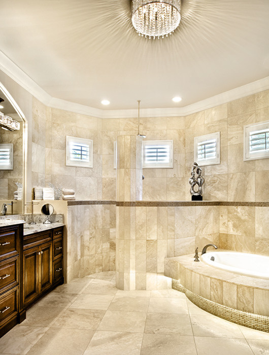 Inredning av ett klassiskt badrum, med ett undermonterad handfat, luckor med upphöjd panel, skåp i mörkt trä, granitbänkskiva, ett platsbyggt badkar, en dusch/badkar-kombination, beige kakel, stenkakel, grå väggar och travertin golv