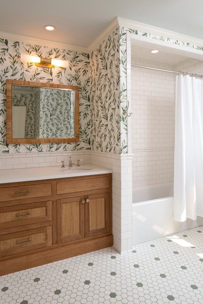 На фото: ванная комната в средиземноморском стиле с фасадами с декоративным кантом, фасадами цвета дерева среднего тона, ванной в нише, унитазом-моноблоком, белой плиткой, керамической плиткой, белыми стенами, полом из керамогранита, врезной раковиной, столешницей из искусственного кварца, зеленым полом, душем с распашными дверями, белой столешницей, тумбой под одну раковину, встроенной тумбой и обоями на стенах с