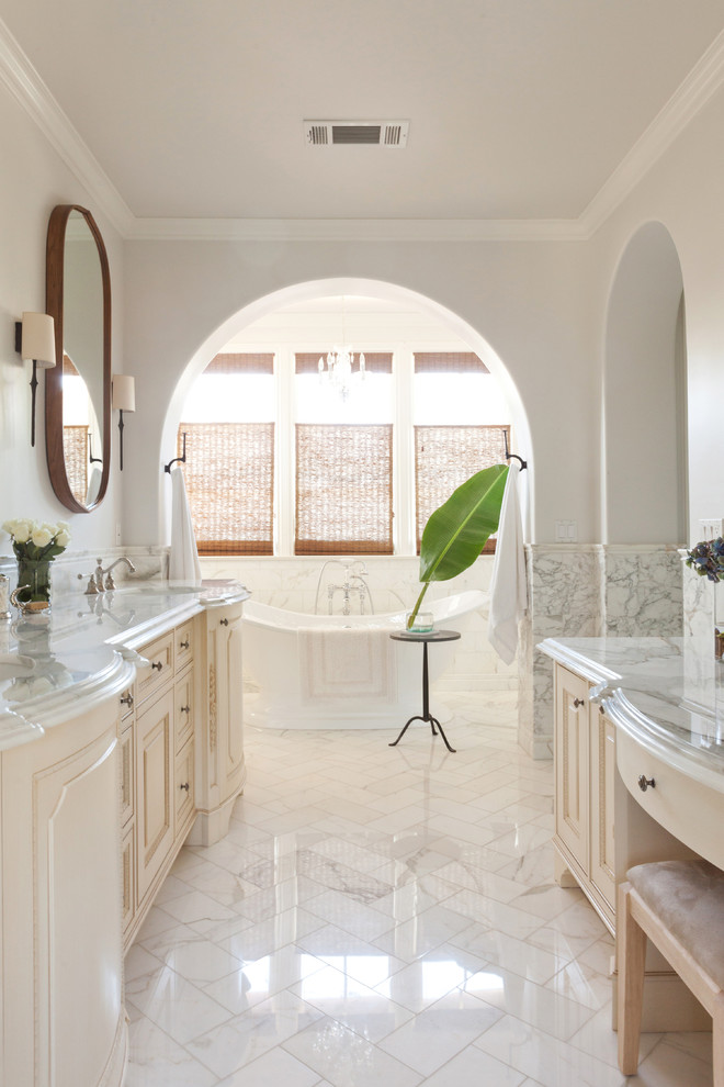 Inspiration for a mediterranean bathroom in Los Angeles with a submerged sink, raised-panel cabinets, beige cabinets, a freestanding bath and white walls.