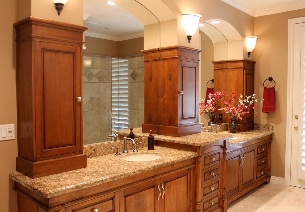 Example of a large tuscan master beige tile and stone tile limestone floor double shower design in Los Angeles with raised-panel cabinets, dark wood cabinets, granite countertops, an undermount sink and beige walls