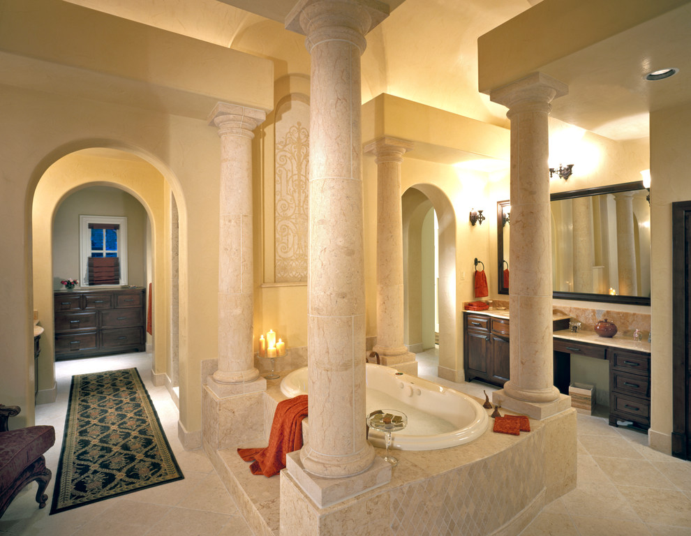Mediterranean bathroom in Austin with raised-panel cabinets, dark wood cabinets, a built-in bath and beige tiles.