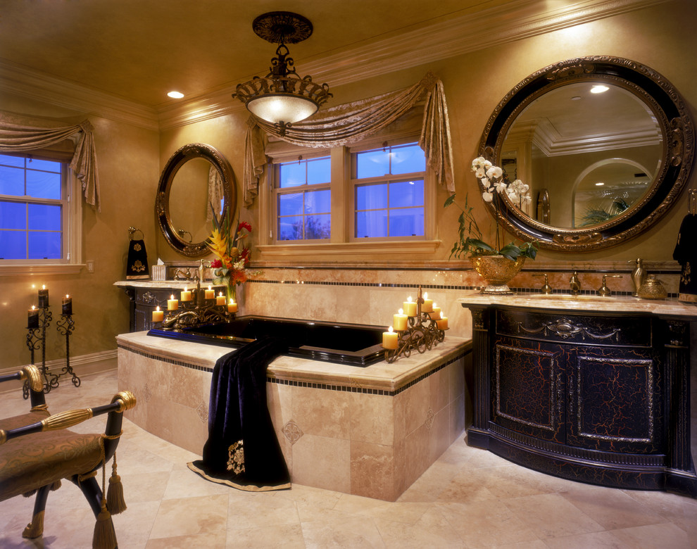 オレンジカウンティにある地中海スタイルのおしゃれな浴室 (アンダーカウンター洗面器、濃色木目調キャビネット、ドロップイン型浴槽、ベージュのタイル、トラバーチンタイル) の写真