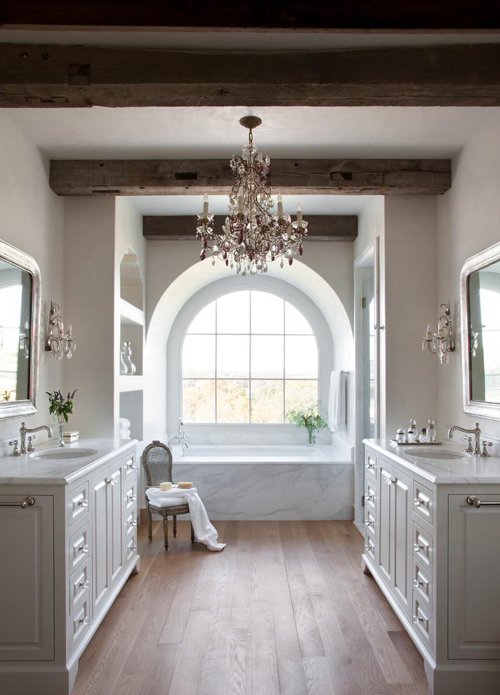 Mediterranes Badezimmer mit Unterbauwaschbecken, profilierten Schrankfronten, weißen Schränken, Unterbauwanne, weißer Wandfarbe und braunem Holzboden in Austin