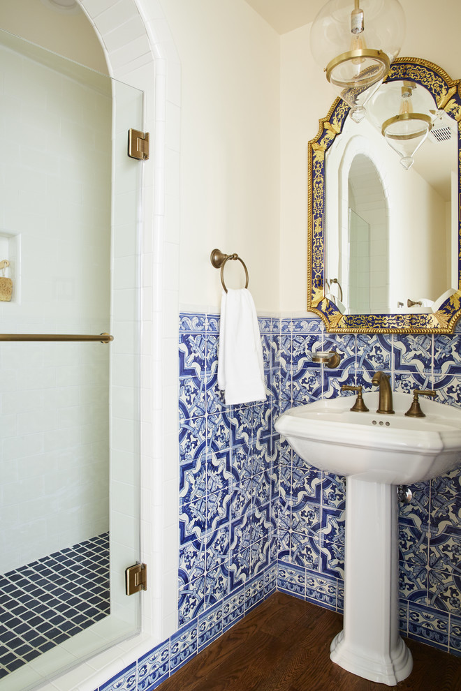 Inredning av ett medelhavsstil badrum med dusch, med blå kakel, flerfärgad kakel, vit kakel, ett piedestal handfat, dusch med gångjärnsdörr och mörkt trägolv