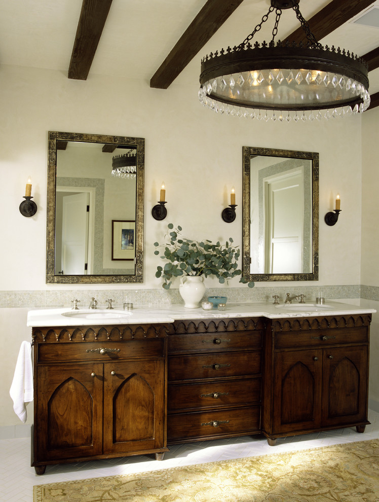 Design ideas for a mediterranean bathroom in Los Angeles with a submerged sink, recessed-panel cabinets, dark wood cabinets and feature lighting.