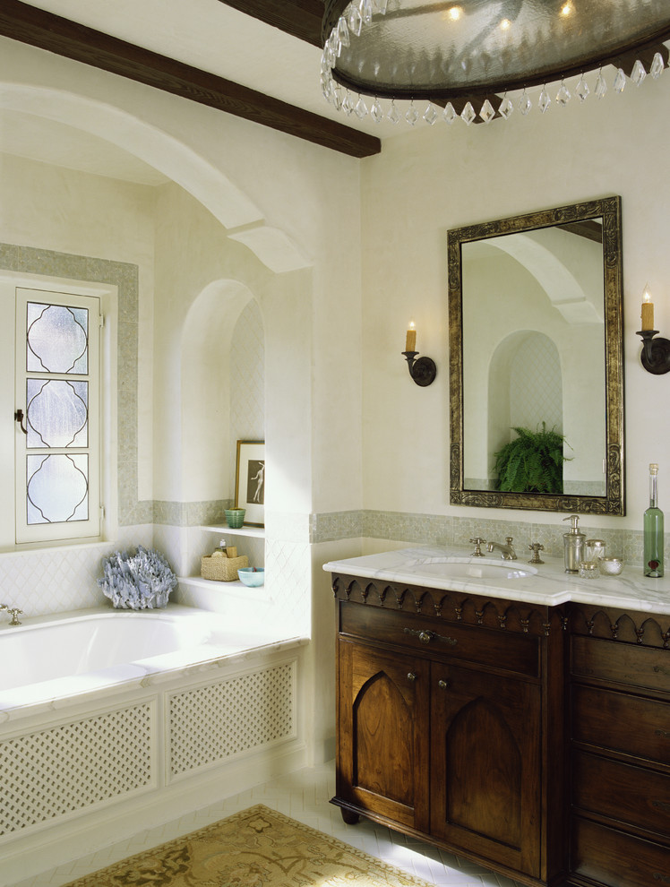 ロサンゼルスにある地中海スタイルのおしゃれな浴室 (濃色木目調キャビネット、アルコーブ型浴槽、落し込みパネル扉のキャビネット) の写真