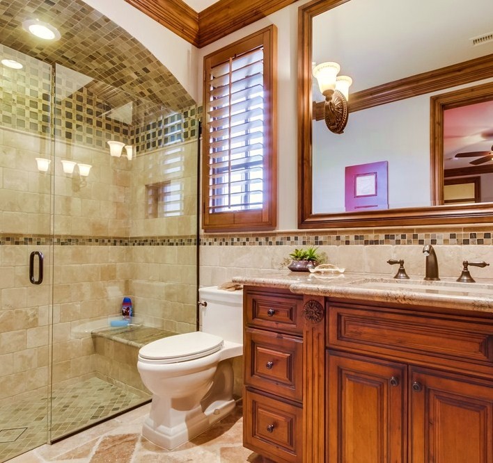 Photo of a medium sized mediterranean shower room bathroom in San Diego with raised-panel cabinets, medium wood cabinets, a built-in bath, a double shower, a one-piece toilet, beige tiles, stone tiles, beige walls, limestone flooring, marble worktops, beige floors, an open shower and multi-coloured worktops.