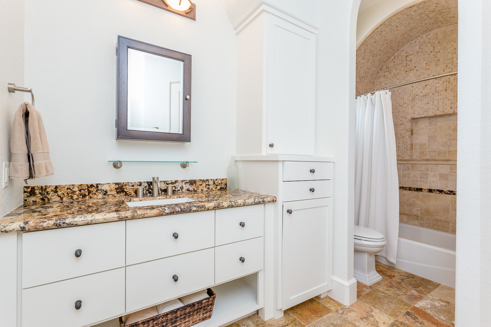 Inredning av ett medelhavsstil stort beige beige badrum, med skåp i shakerstil, vita skåp, ett badkar i en alkov, en dusch/badkar-kombination, beige kakel, travertinkakel, vita väggar, travertin golv, ett undermonterad handfat, granitbänkskiva, beiget golv och dusch med duschdraperi