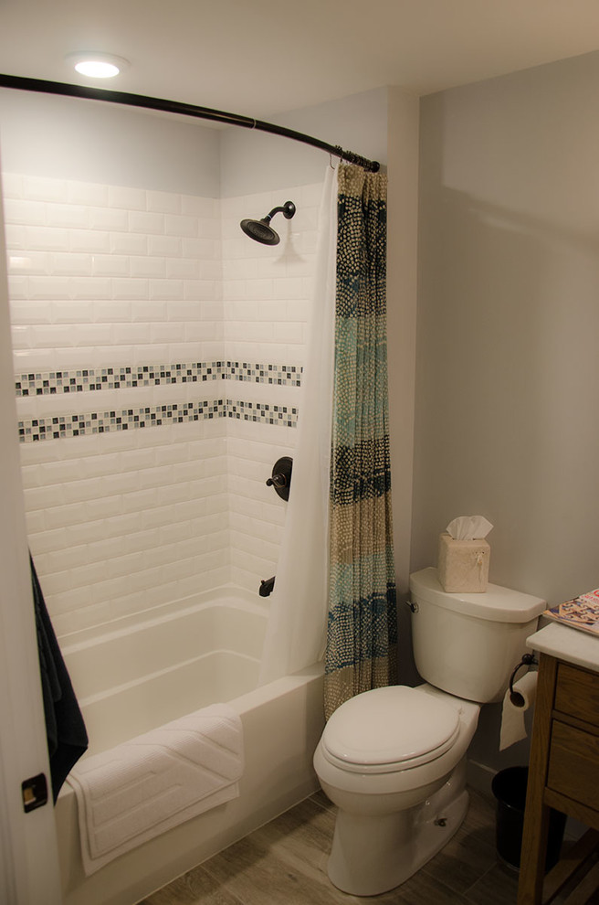 Photo of a medium sized classic shower room bathroom in New York with freestanding cabinets, medium wood cabinets, an alcove bath, a shower/bath combination, a two-piece toilet, white tiles, white walls and a shower curtain.
