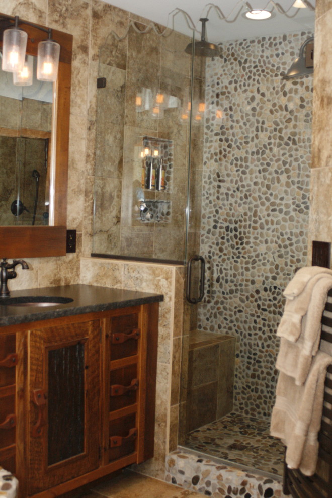 Large rustic ensuite bathroom in Other with freestanding cabinets, dark wood cabinets, a corner bath, an alcove shower, beige tiles, travertine tiles, beige walls, travertine flooring, a submerged sink, soapstone worktops, brown floors and a hinged door.