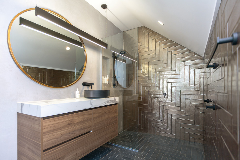 Aménagement d'une salle de bain contemporaine en bois foncé de taille moyenne avec un plan de toilette en stratifié, un placard à porte plane, un carrelage marron, un mur gris, une vasque, un sol noir et aucune cabine.