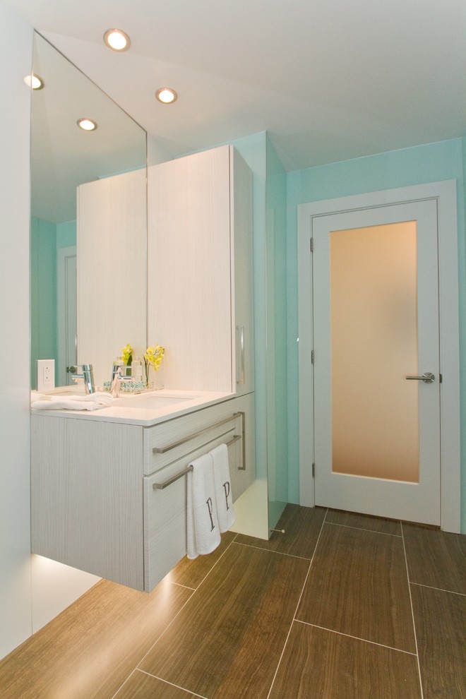 Cette photo montre une salle de bain tendance en bois clair avec un lavabo encastré et un placard à porte plane.