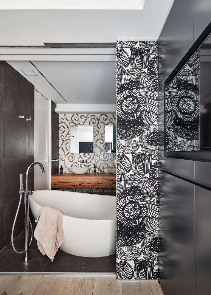 Mittelgroßes Modernes Badezimmer En Suite mit flächenbündigen Schrankfronten, hellbraunen Holzschränken, freistehender Badewanne, grauen Fliesen, weißer Wandfarbe, Aufsatzwaschbecken, Waschtisch aus Holz und grauem Boden in Melbourne
