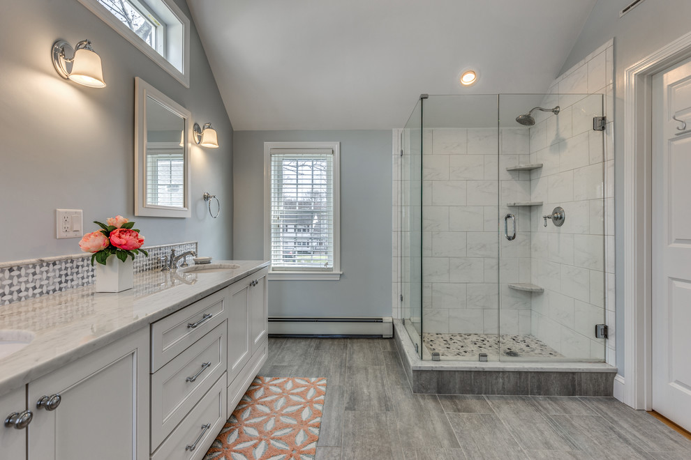 Inspiration for a large transitional master white tile and marble tile porcelain tile and gray floor corner shower remodel in Boston with beaded inset cabinets, white cabinets, white walls, an undermount sink, marble countertops and a hinged shower door