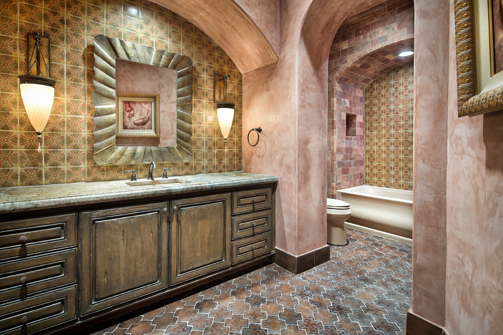 Diseño de cuarto de baño mediterráneo con lavabo bajoencimera, armarios con paneles con relieve, puertas de armario de madera en tonos medios, bañera empotrada, combinación de ducha y bañera y baldosas y/o azulejos multicolor