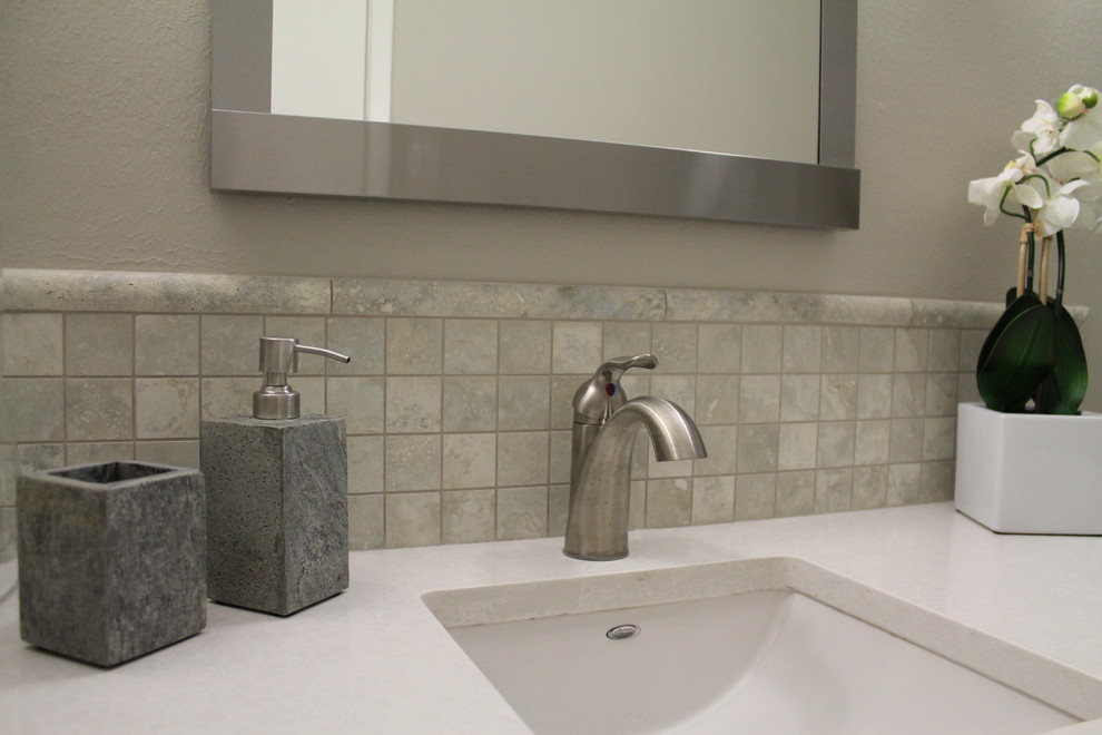 Klassisk inredning av ett mellanstort badrum, med ett undermonterad handfat, luckor med infälld panel, grå skåp, bänkskiva i kvarts, ett badkar i en alkov, en dusch/badkar-kombination, en toalettstol med separat cisternkåpa, grå kakel, porslinskakel, grå väggar och klinkergolv i porslin