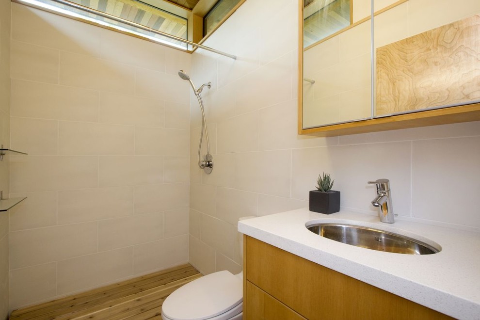 Inspiration for a contemporary shower room bathroom in Vancouver with a submerged sink, flat-panel cabinets, light wood cabinets, engineered stone worktops, a walk-in shower, a one-piece toilet, white tiles, ceramic tiles, white walls and ceramic flooring.