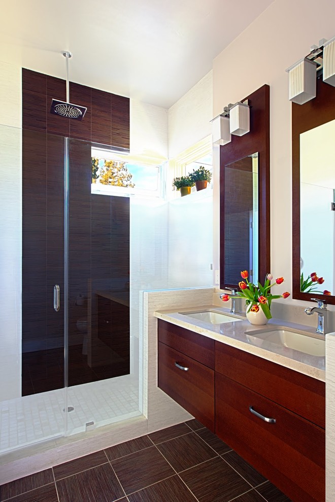 На фото: ванная комната в современном стиле с врезной раковиной, плоскими фасадами, темными деревянными фасадами, душем в нише, белой плиткой и окном