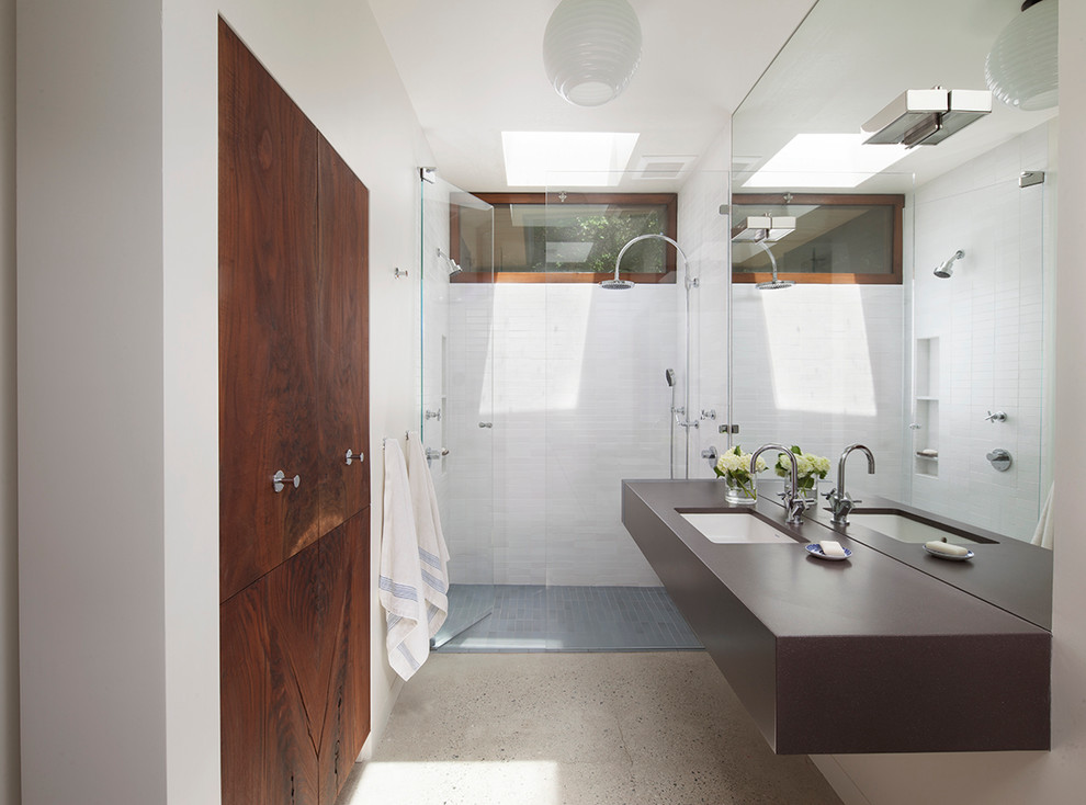 Diseño de cuarto de baño actual, de tamaño medio, con lavabo bajoencimera, ducha empotrada, baldosas y/o azulejos blancos, paredes blancas, suelo de cemento, aseo y ducha y puertas de armario de madera en tonos medios