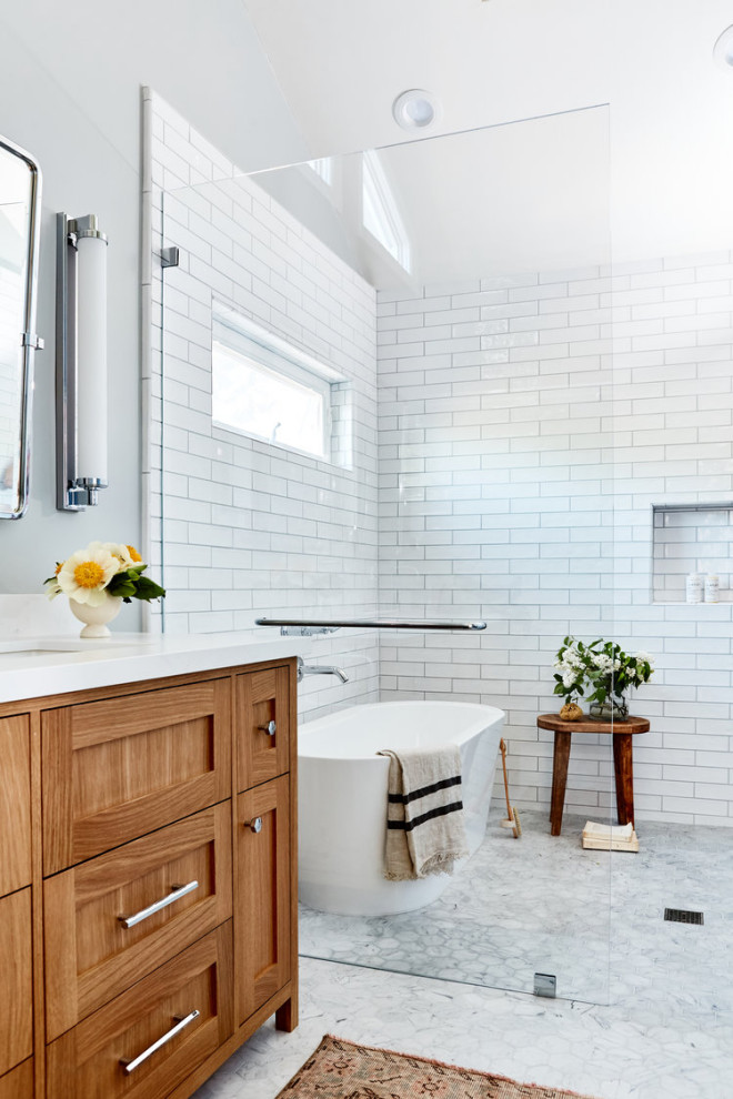 Inredning av ett klassiskt vit vitt badrum, med skåp i shakerstil, skåp i mellenmörkt trä, ett fristående badkar, våtrum, vit kakel, tunnelbanekakel, grå väggar, marmorgolv, ett undermonterad handfat och vitt golv