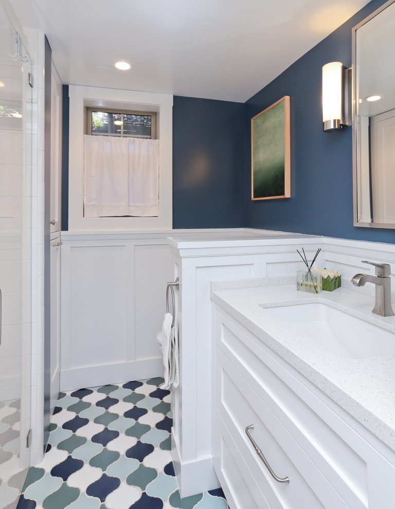 Klassisk inredning av ett badrum, med ett undermonterad handfat, skåp i shakerstil, vita skåp, bänkskiva i kvartsit, en dusch i en alkov, blå kakel, perrakottakakel, blå väggar och klinkergolv i terrakotta