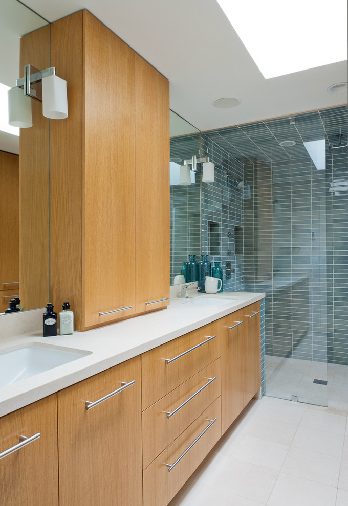 Diseño de cuarto de baño contemporáneo con lavabo bajoencimera, armarios con paneles lisos, puertas de armario de madera oscura, ducha a ras de suelo y baldosas y/o azulejos azules
