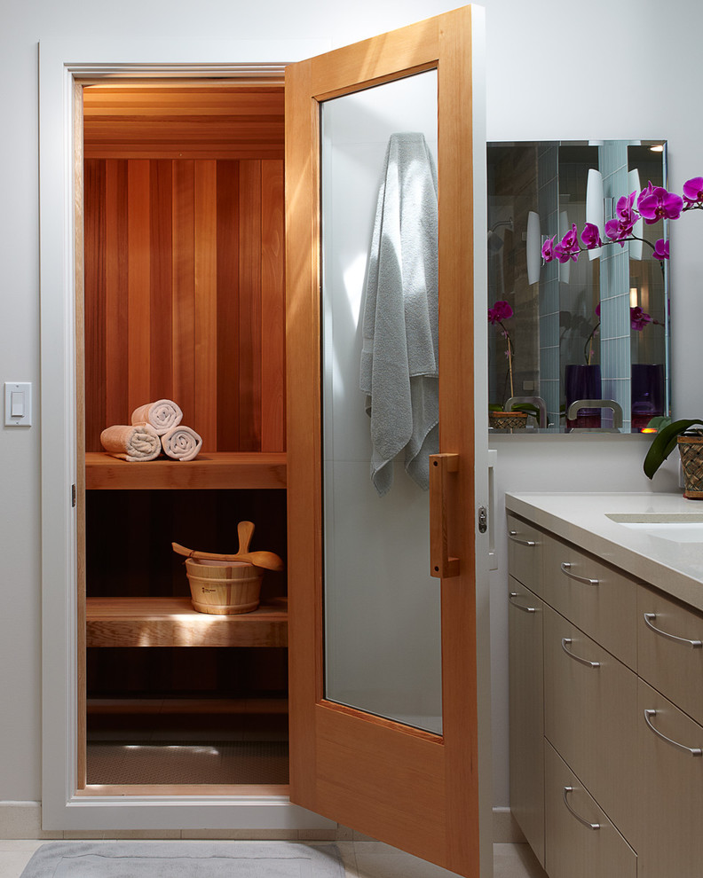 Свежая идея для дизайна: ванная комната среднего размера в современном стиле с плоскими фасадами, бежевыми фасадами, душем в нише, раздельным унитазом, синей плиткой, стеклянной плиткой, серыми стенами, полом из керамической плитки, душевой кабиной, врезной раковиной, столешницей из искусственного камня, бежевым полом и душем с распашными дверями - отличное фото интерьера