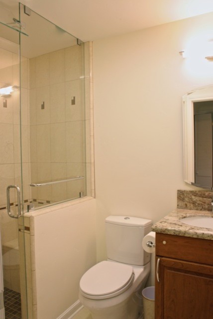 Inredning av ett klassiskt mellanstort badrum med dusch, med ett undermonterad handfat, luckor med upphöjd panel, skåp i mellenmörkt trä, bänkskiva i kvarts, en öppen dusch, en toalettstol med hel cisternkåpa, beige kakel, keramikplattor, vita väggar och ljust trägolv