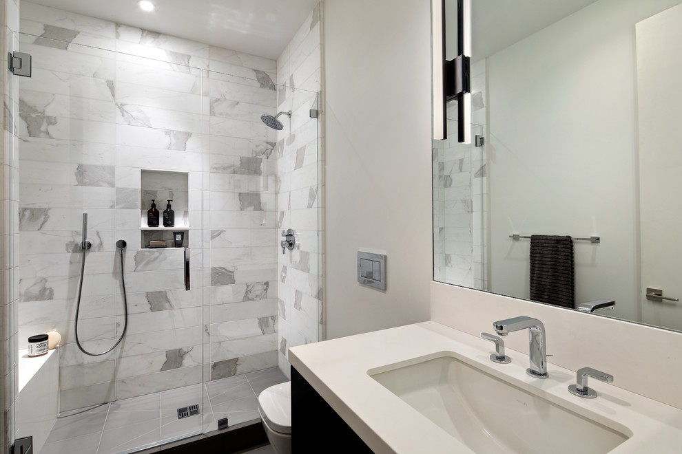 Photo of a small contemporary shower room bathroom in San Francisco with flat-panel cabinets, brown cabinets, an alcove shower, a wall mounted toilet, white tiles, white walls, porcelain flooring, a submerged sink, grey floors, a hinged door and white worktops.