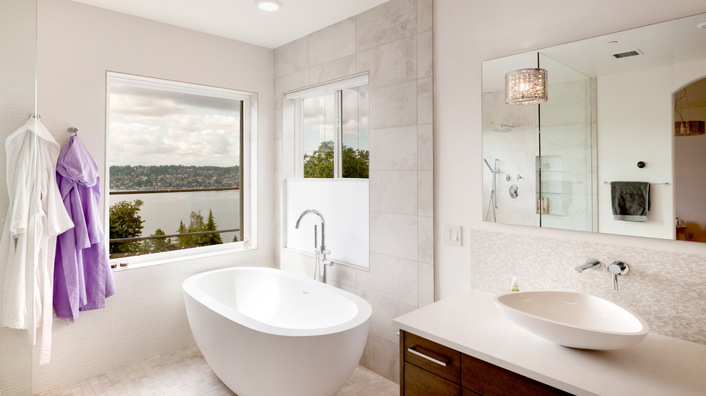 Photo of a modern ensuite bathroom in Seattle with flat-panel cabinets, dark wood cabinets, a freestanding bath, a walk-in shower, grey tiles, ceramic tiles, white walls, porcelain flooring, a vessel sink and engineered stone worktops.